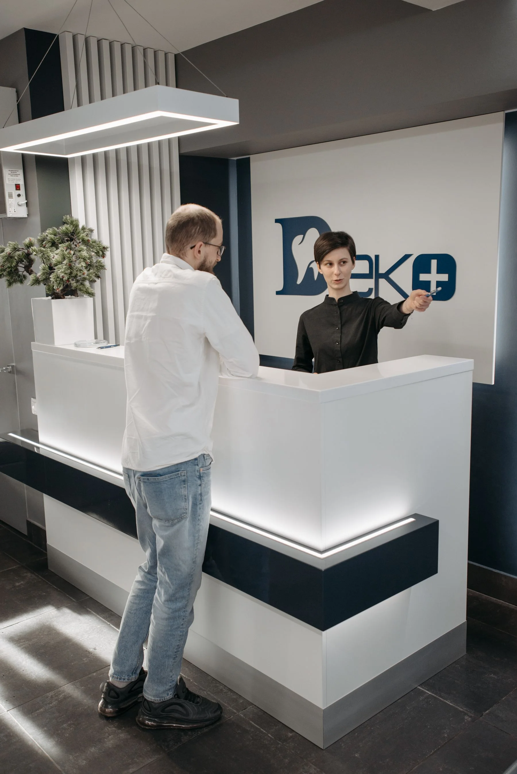 A dental receptionist speaking with a patient at the front desk